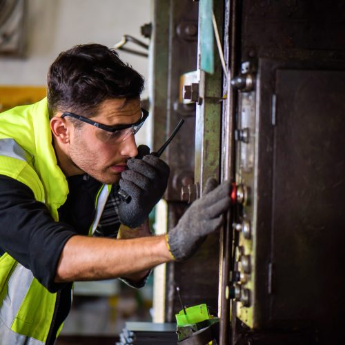 Caucasian engineer mechanic man checking for maintenance pressing metal machine by laptop at factory, worker at industrial concept