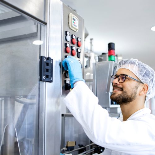 Industrial worker technologist working in food factory by production line machine.