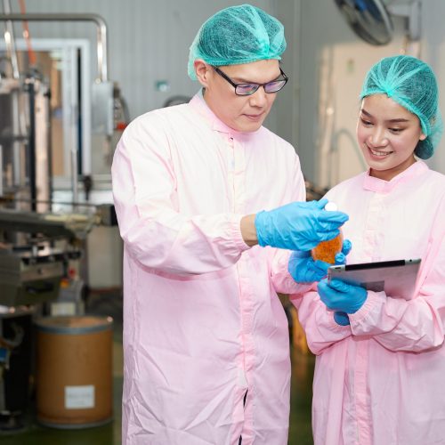 Workers holding and checking basil seed drinks in beverage factory